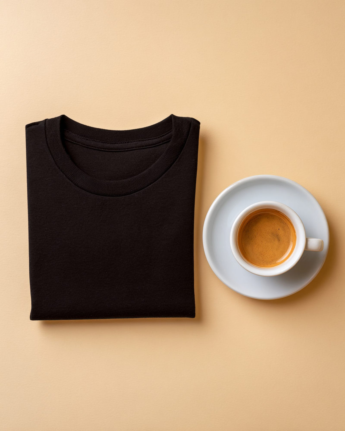 Folded black tee with espresso on cream background, FIOR materials.