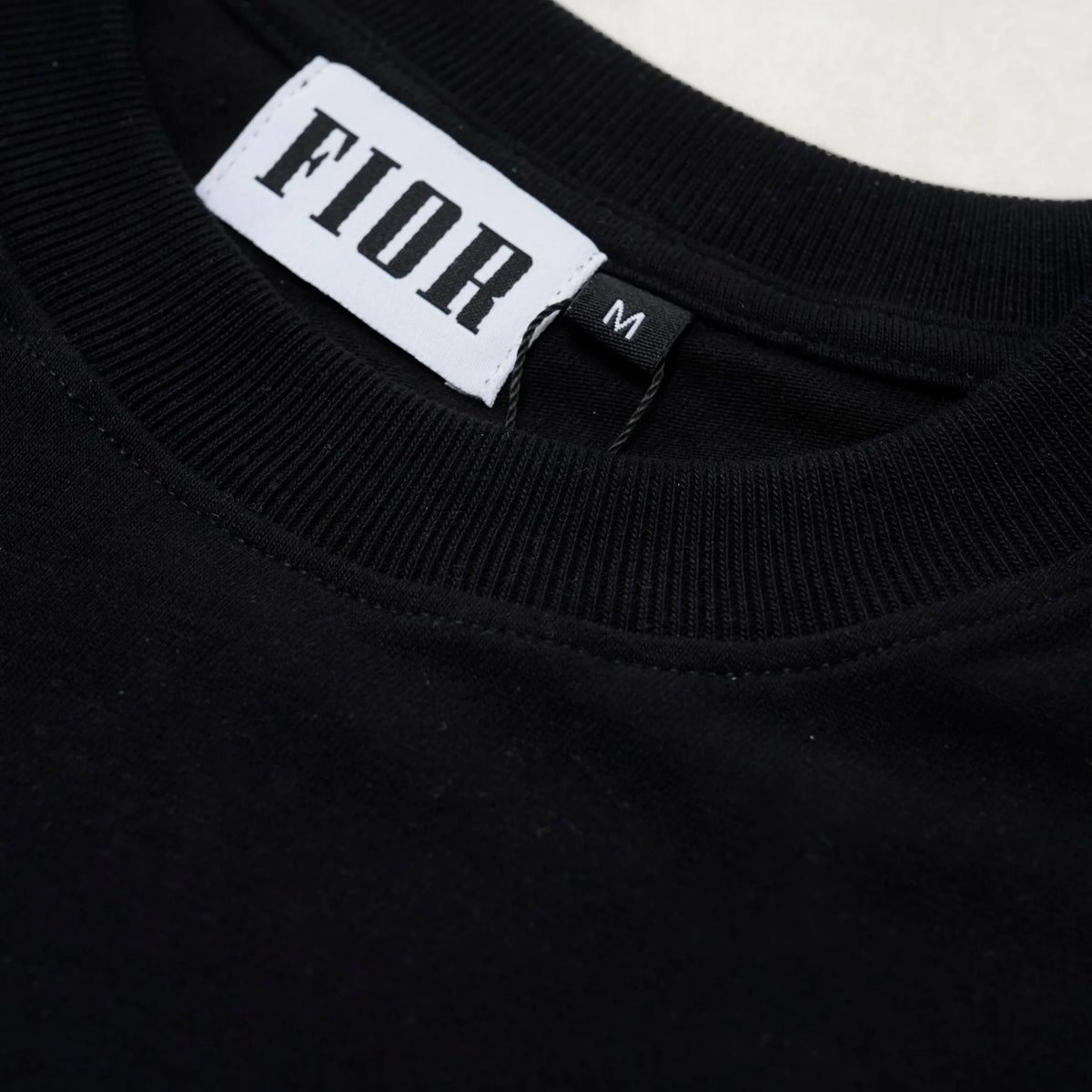Dettaglio colletto e label FIOR su T-shirt nera in cotone, taglia M
